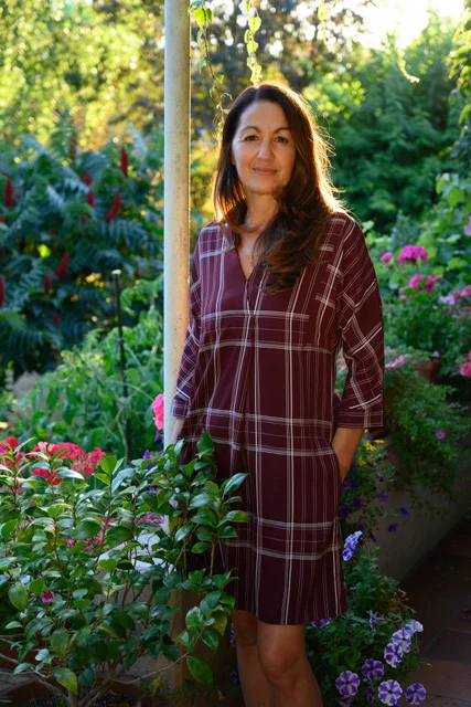 Portrait de Patrizia Buscemi, debout dans un jardin fleuri