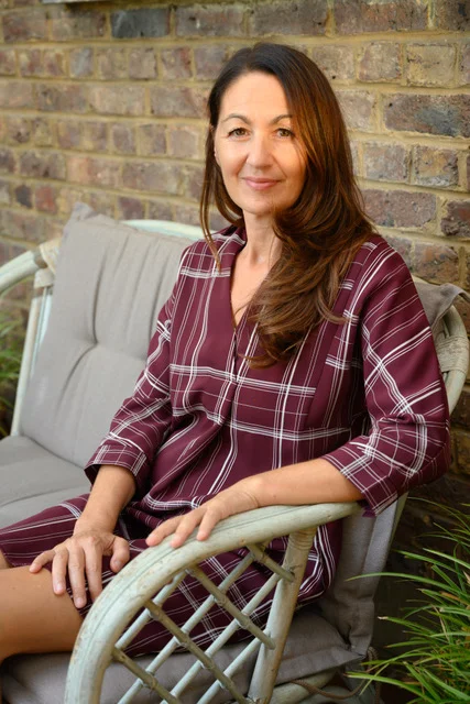 Portrait de Patrizia Buscemi, assise de 3/4 sur un fauteuil de jardin